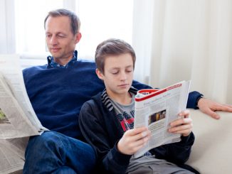 Ein Mann und ein Junge lesen zusammen auf dem Sofa, aber jeder für sich